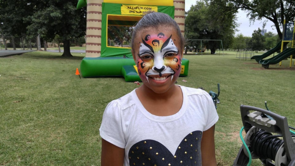 A girl with face paint and a bouncy castle.