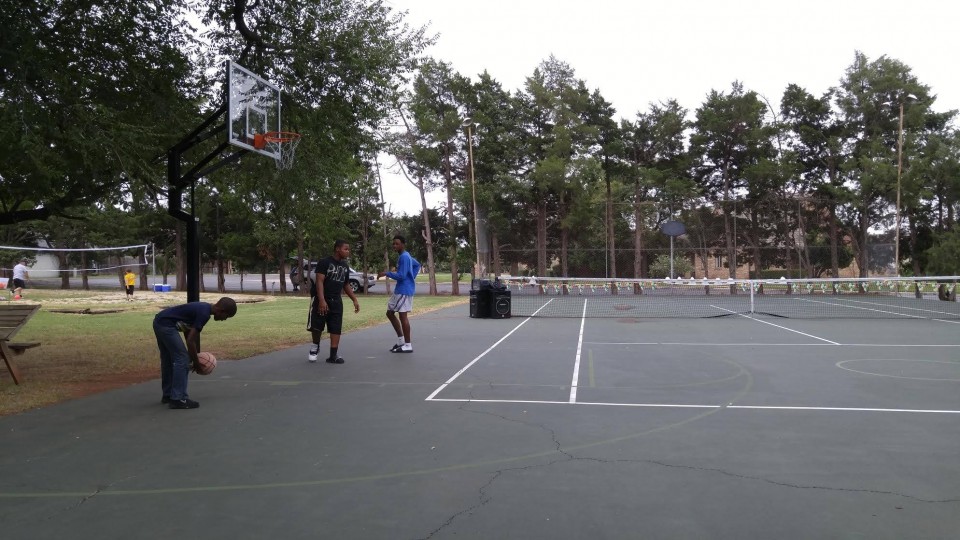 A group of people playing basketball on an outdoor court.