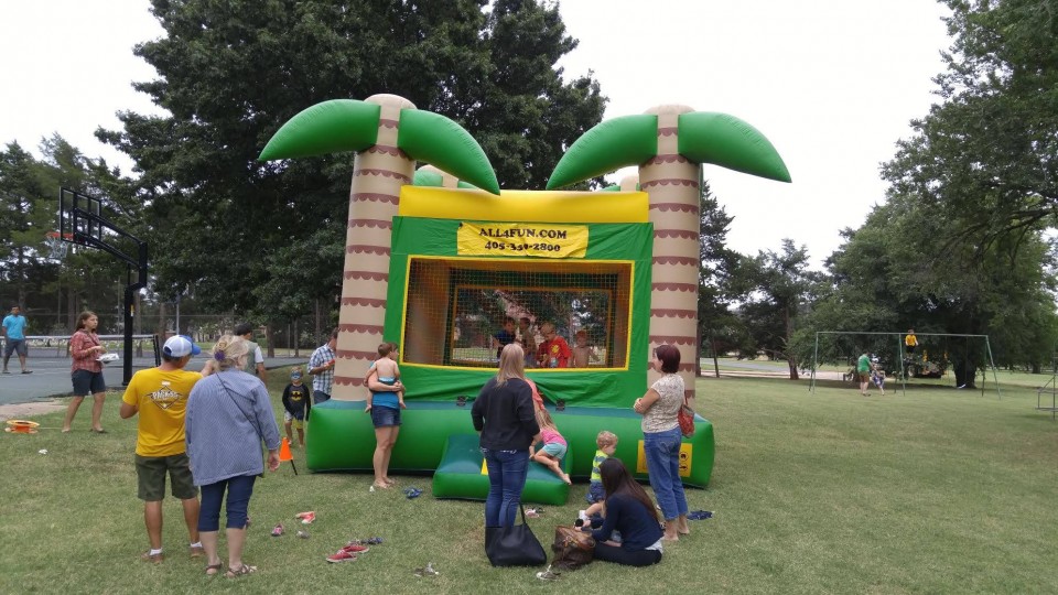A group of people standing around an inflatable bounce house.