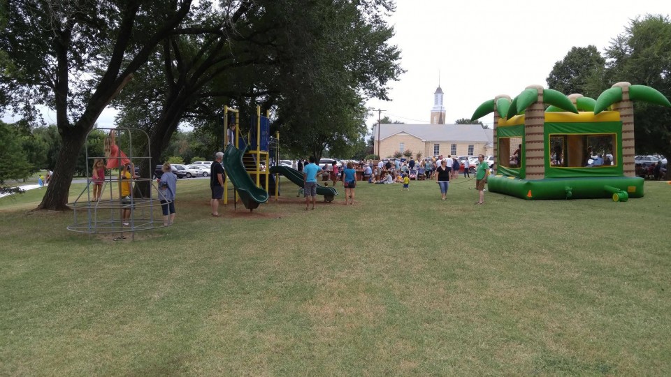 A group of people playing on a playground in a park.