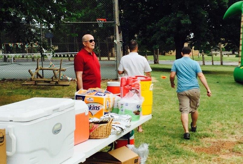 A group of people standing around a table with food and drinks.