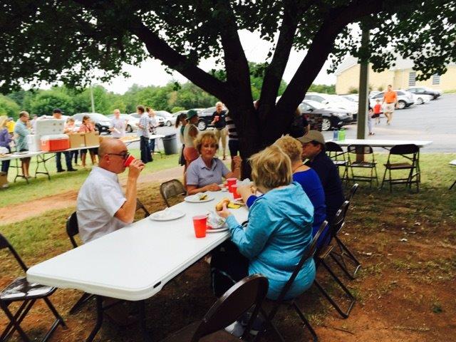 A group of people sitting at a table under a tree.