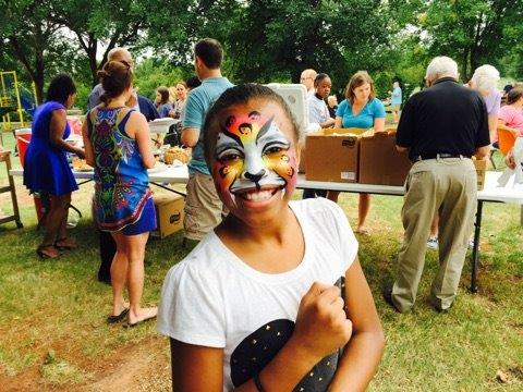 A young girl with a face painted with a lion.