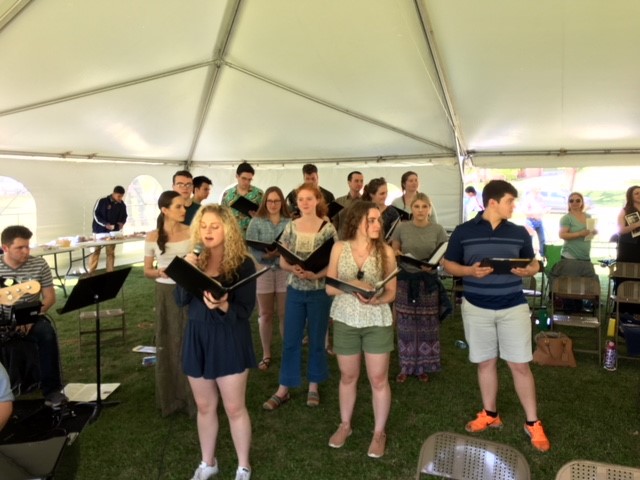 A group of people singing in a tent.