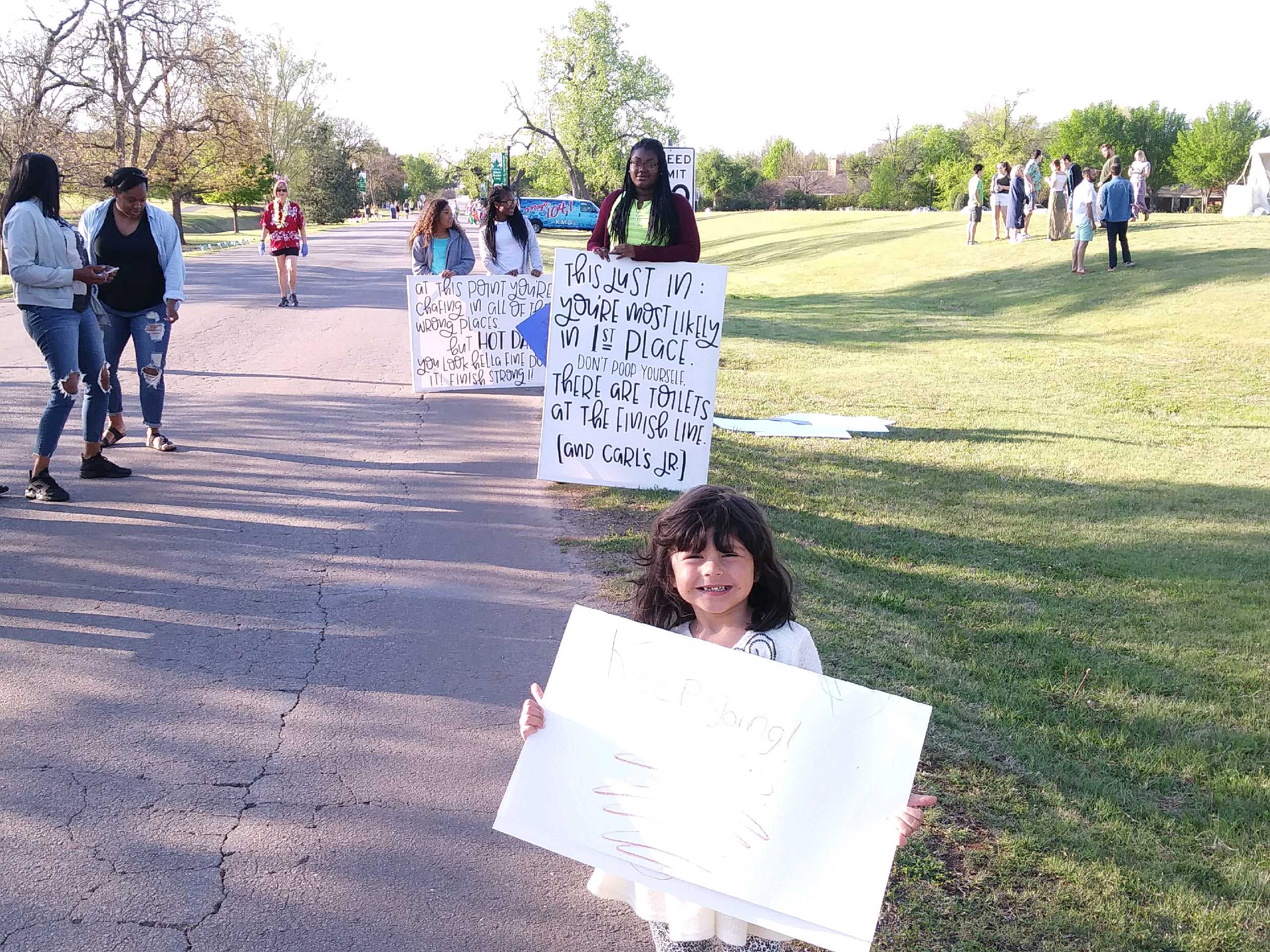 A young girl holding a sign in front of a group of people.