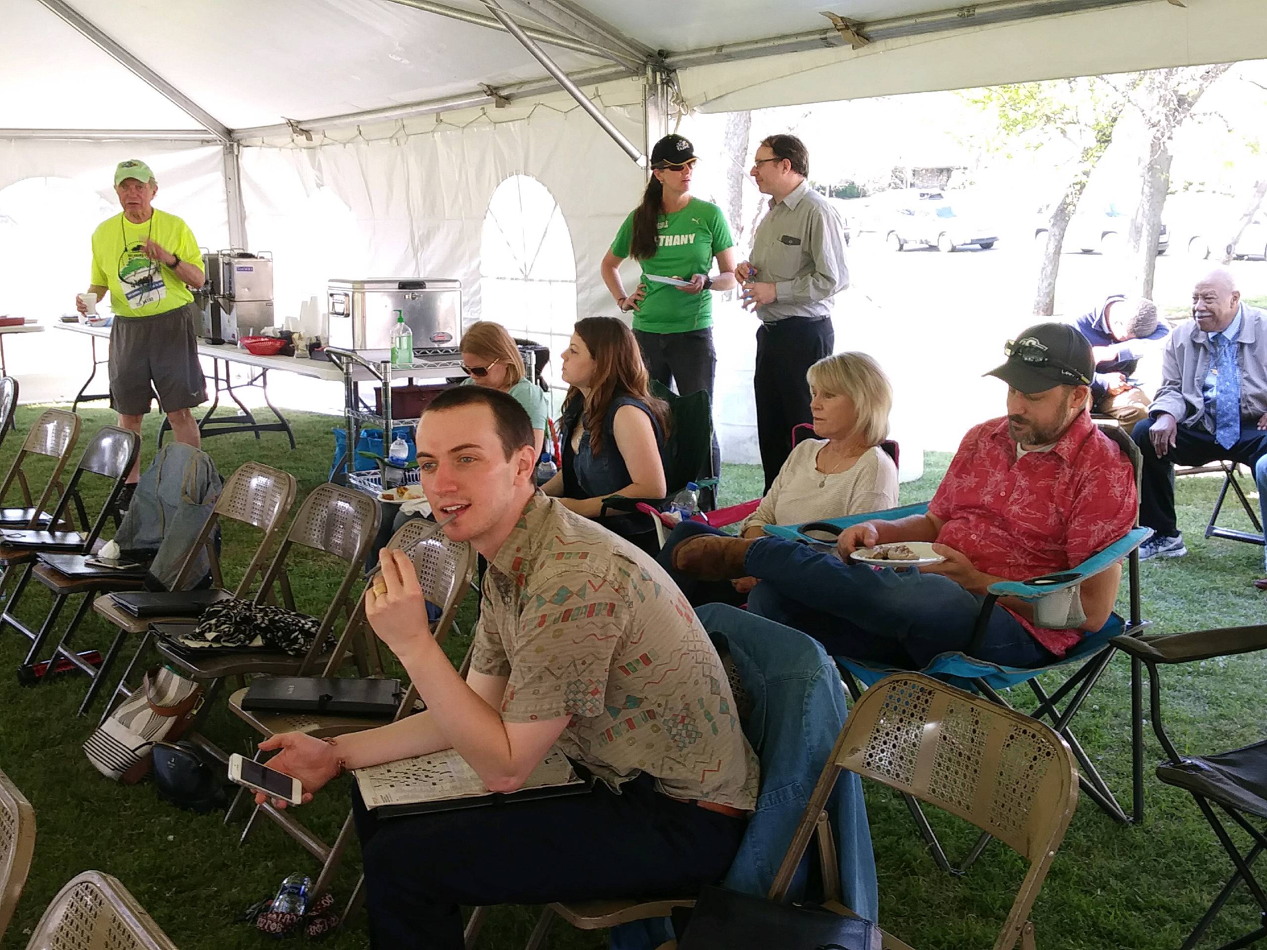 A group of people sitting in chairs under a tent.