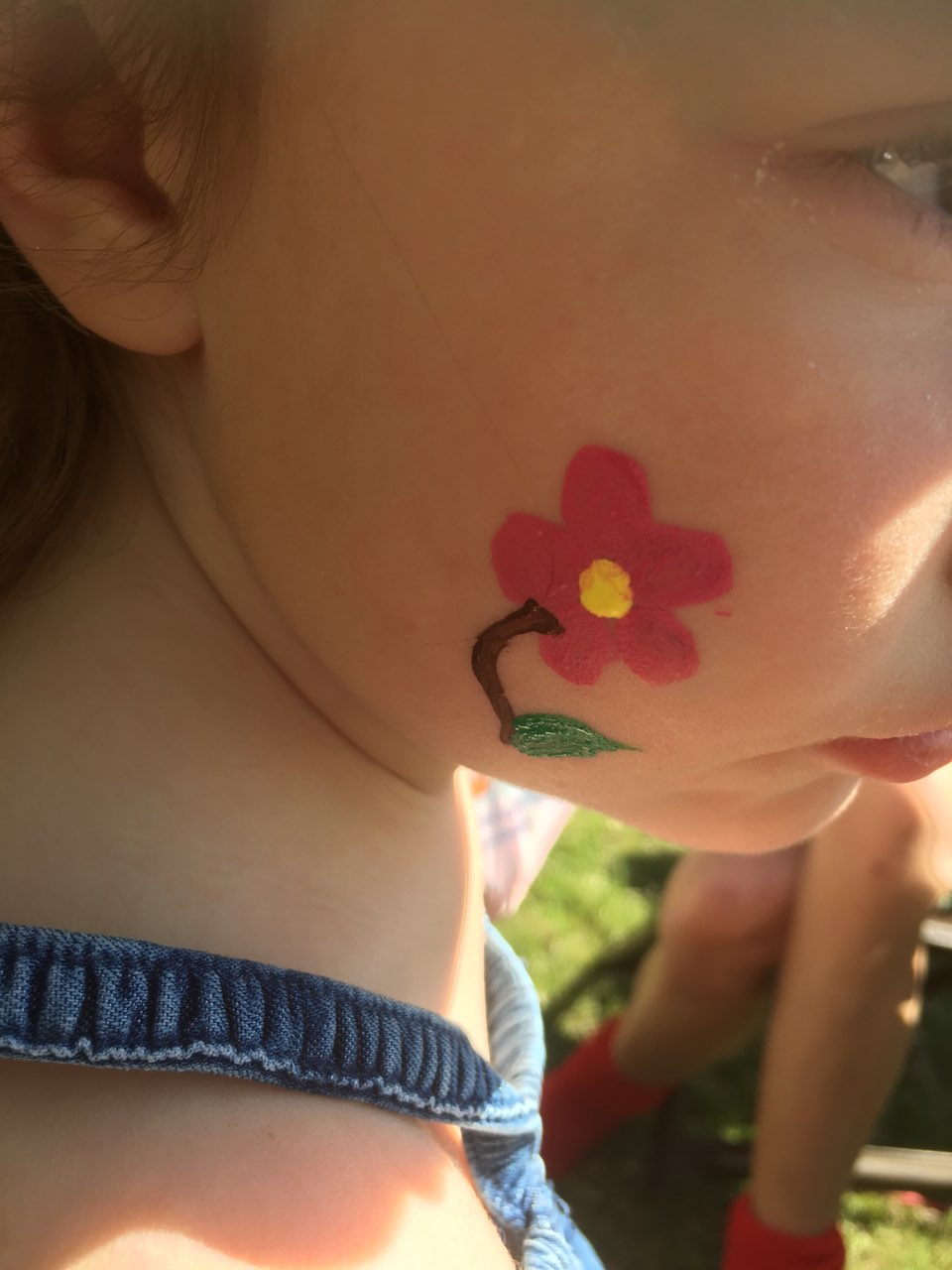 A little girl with a flower painted on her face.