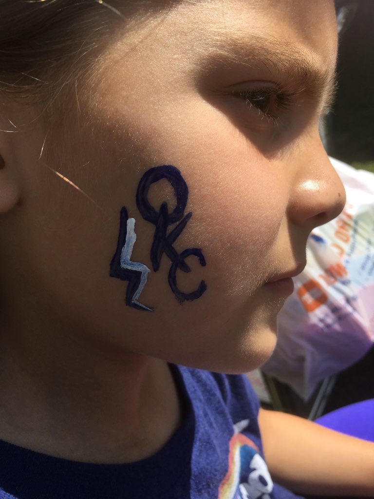 A little girl with a face painted with the oklahoma rangers logo.