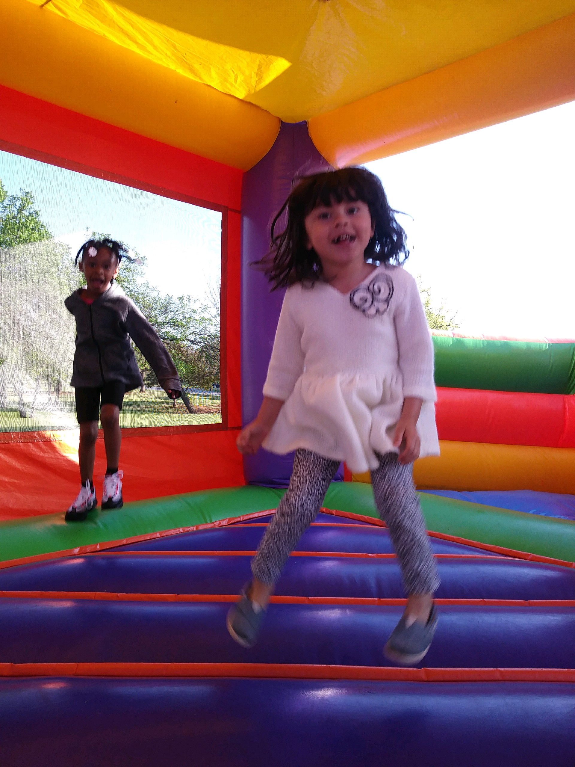 A little girl jumping on a bouncy castle.