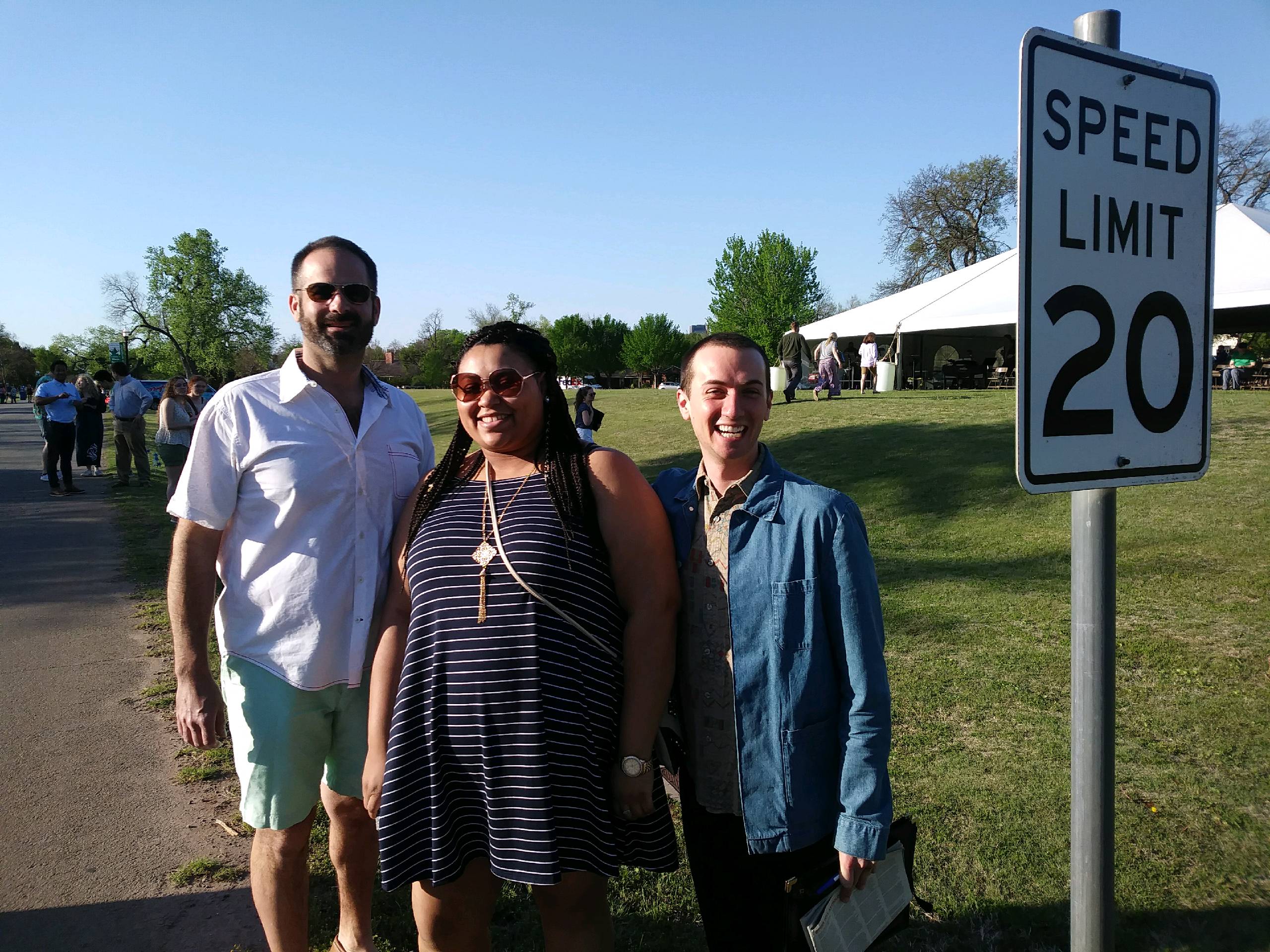 Three people standing in front of a speed limit sign.