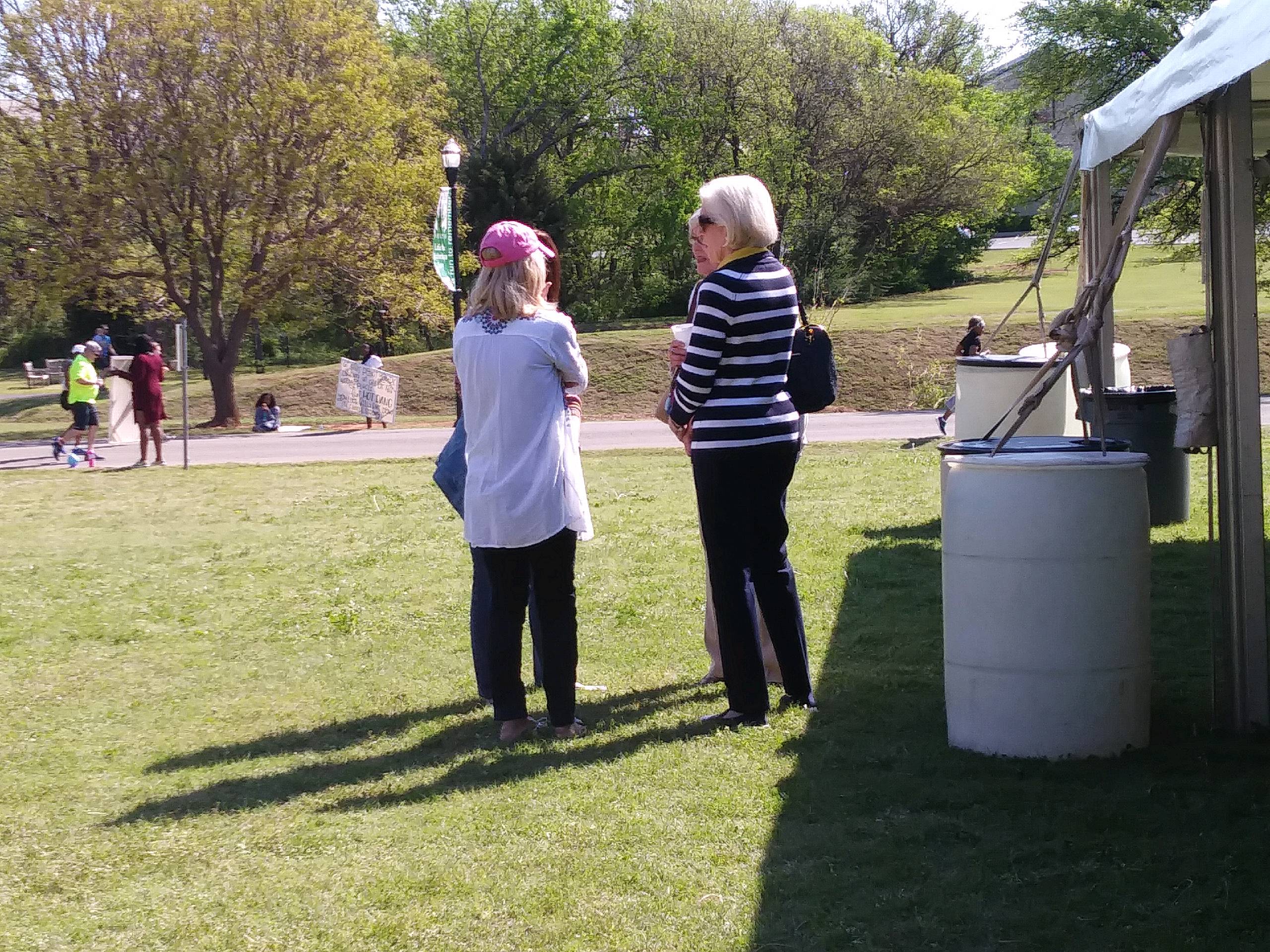 A group of people standing under a tent in a park.