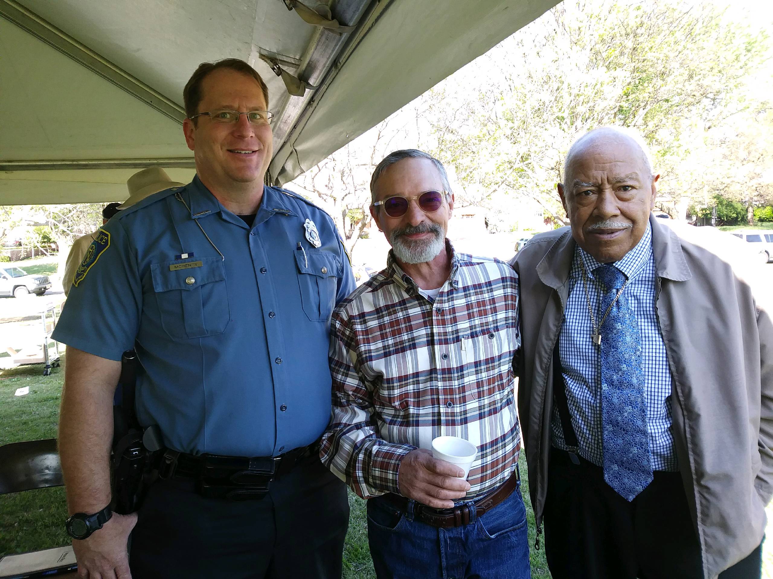 Three men standing next to each other under a tent.