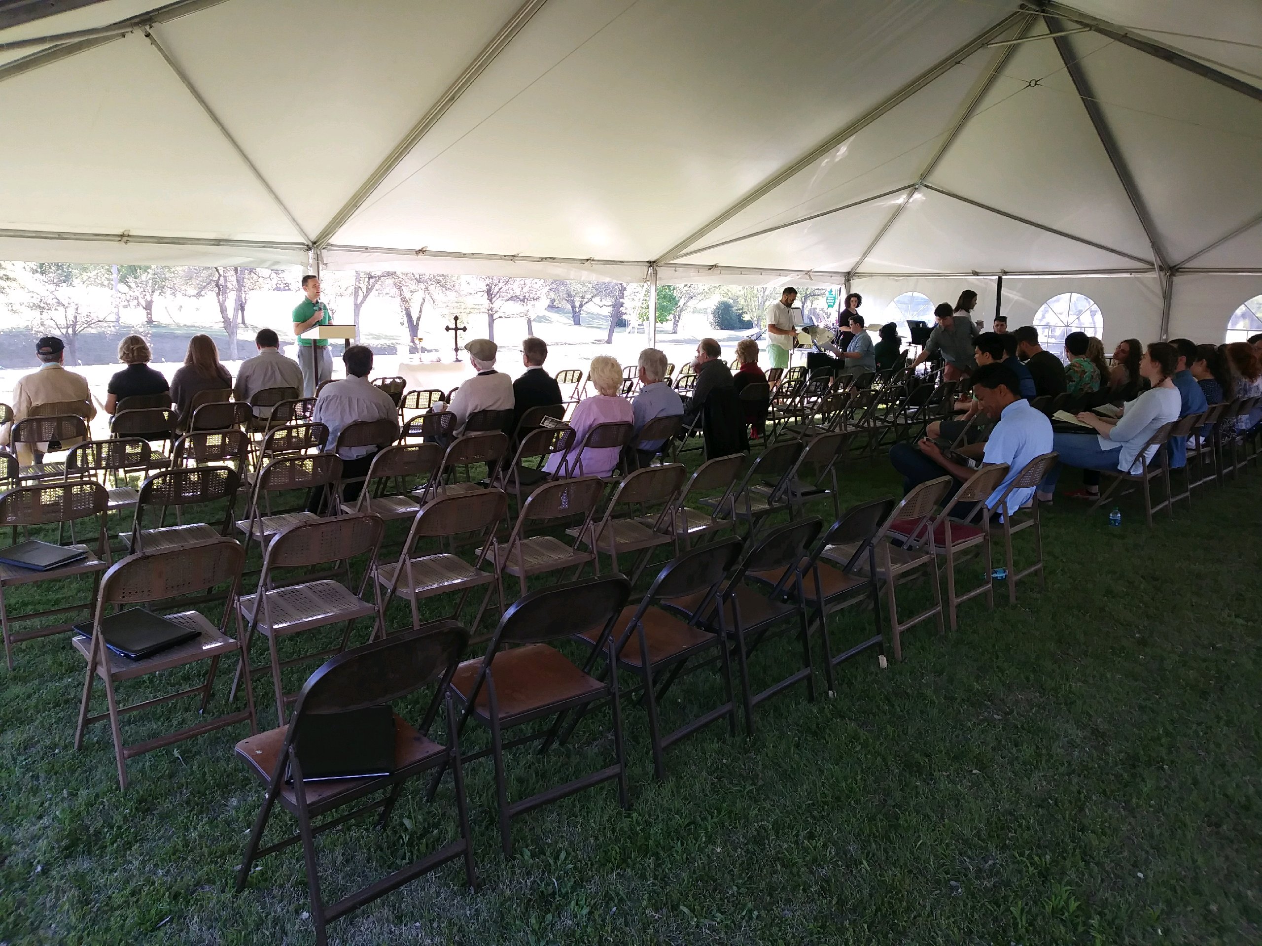 A group of people sitting in chairs under a tent.