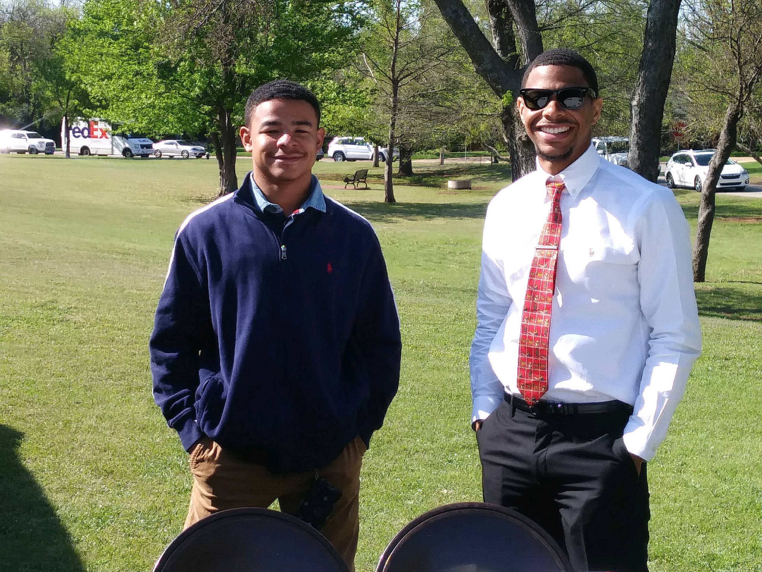Two men posing for a picture in a park.