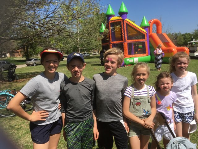 A group of kids posing in front of an inflatable bounce house.