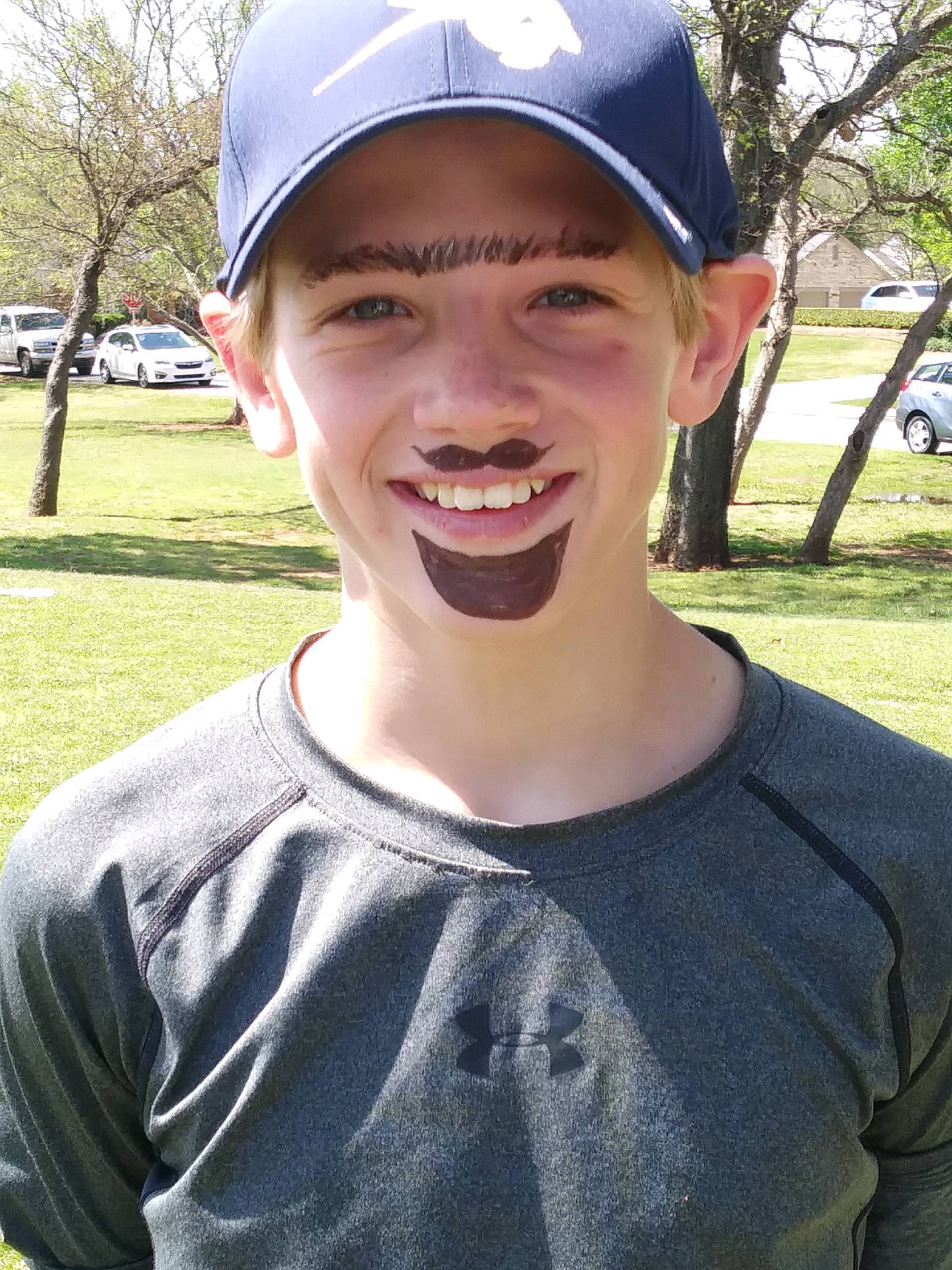 A boy wearing a baseball cap with a mustache.