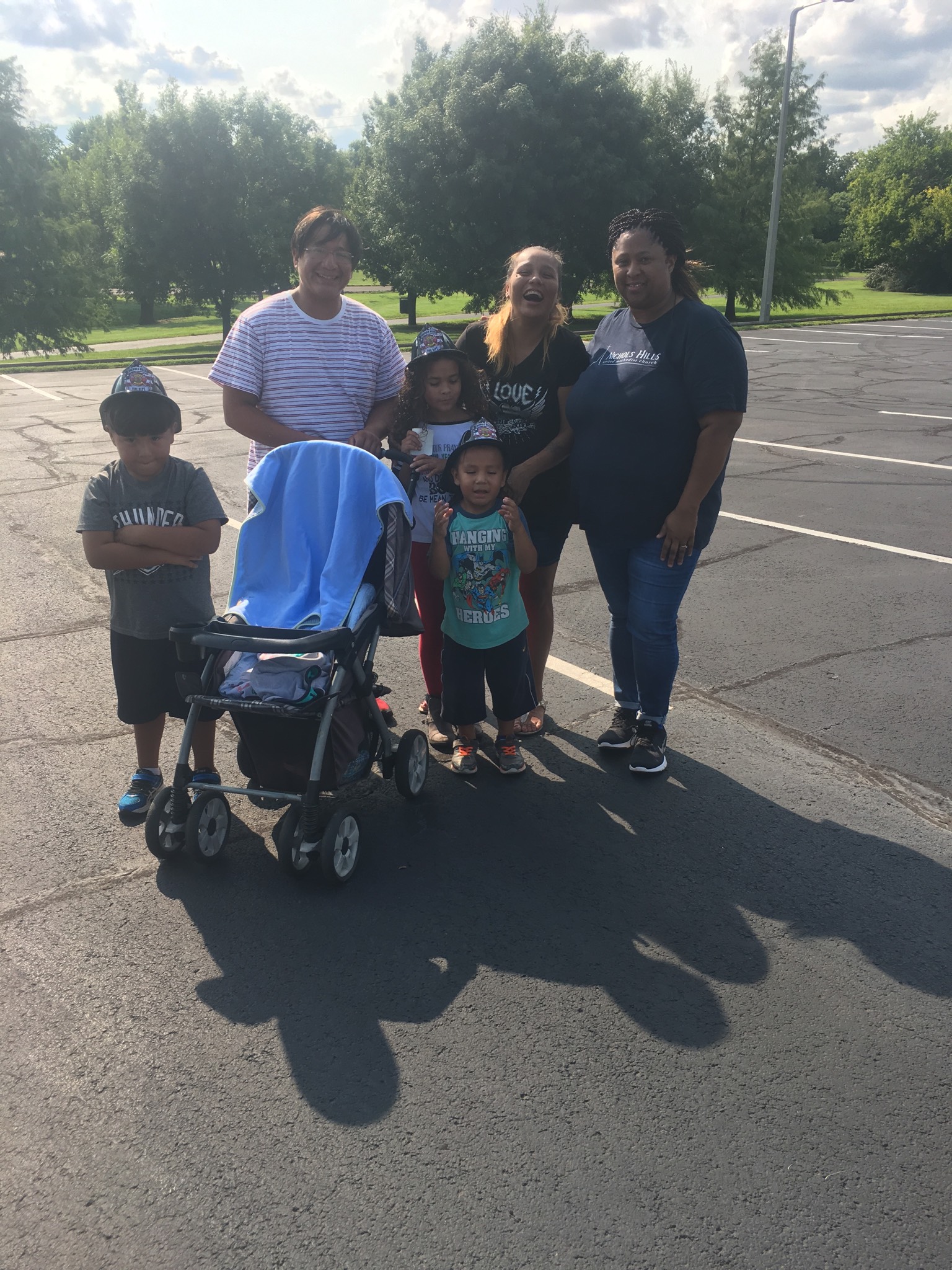 A group of people standing in a parking lot with a stroller.