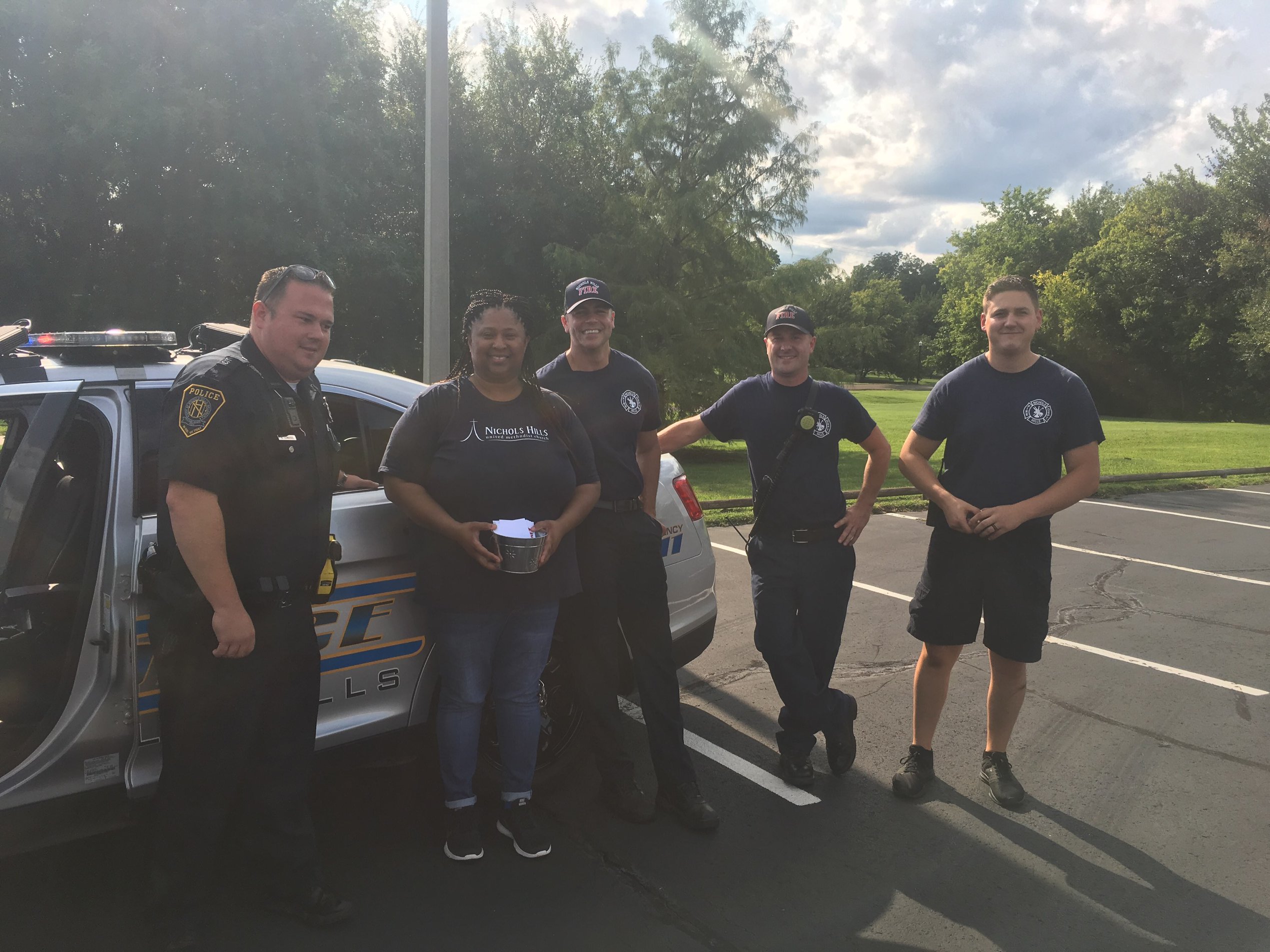 A group of people standing next to a police car.
