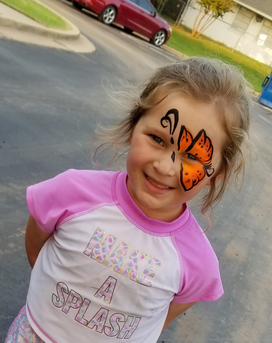A little girl with a butterfly face paint.