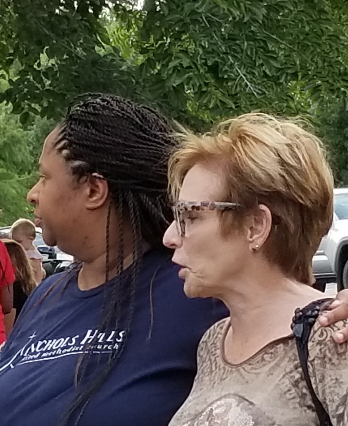 Two women standing next to each other in a parking lot.