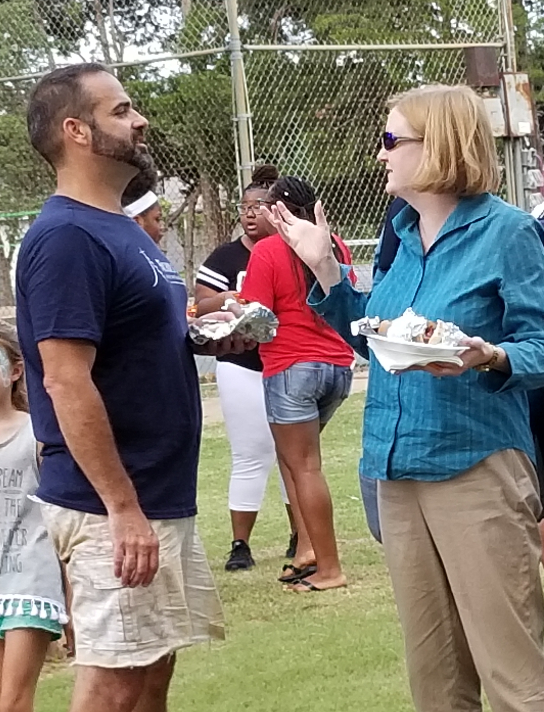 A group of people talking to each other in a field.