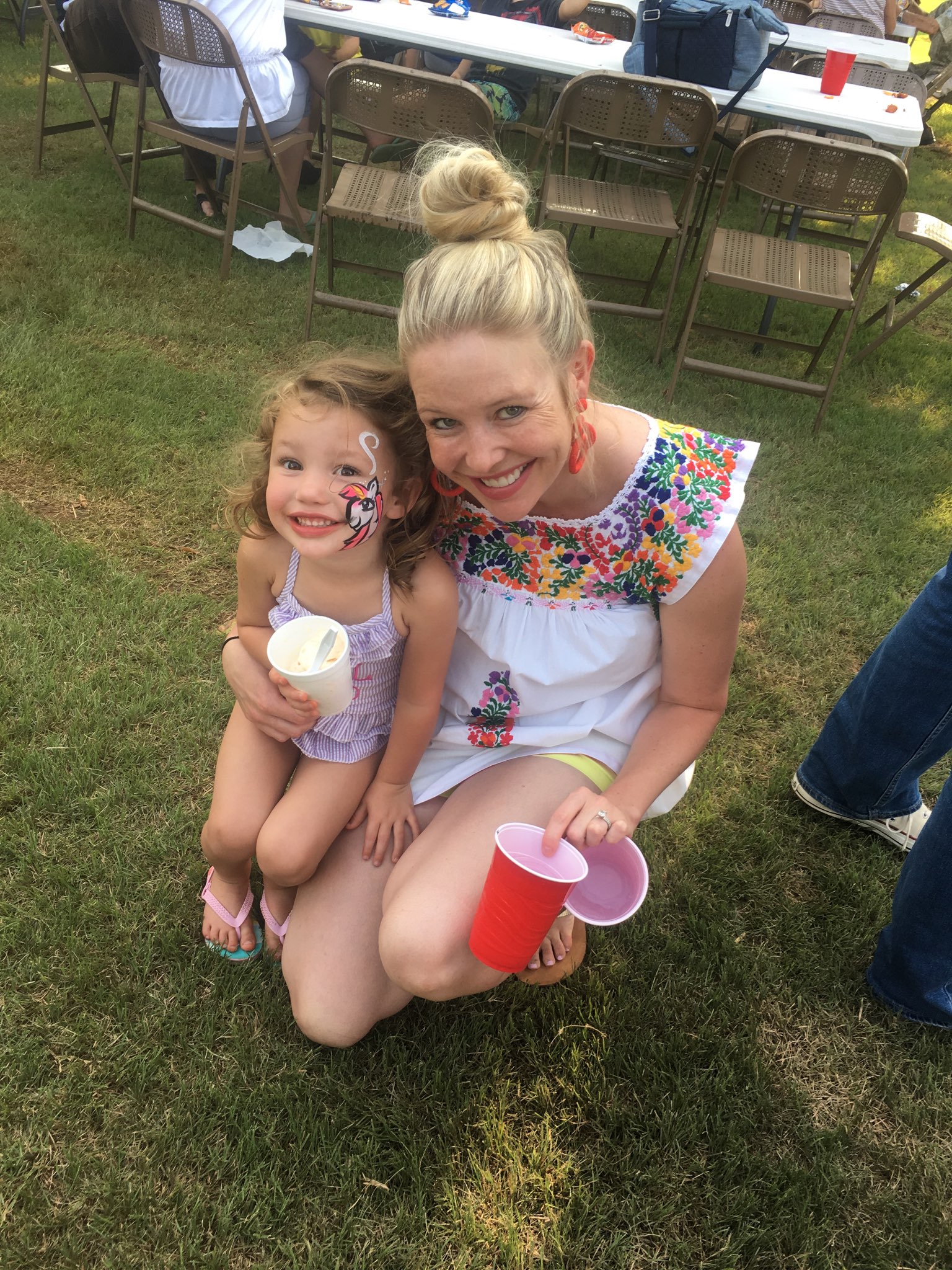 A woman with a little girl and a cup of ice cream.