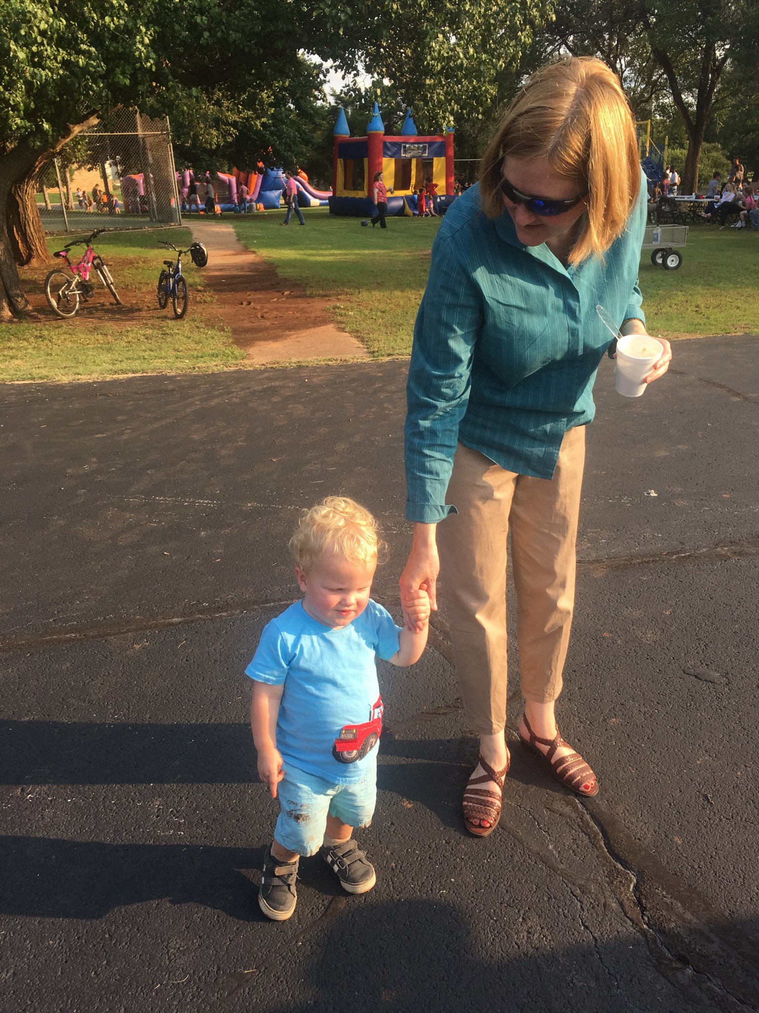 A woman holding a child's hand in a park.