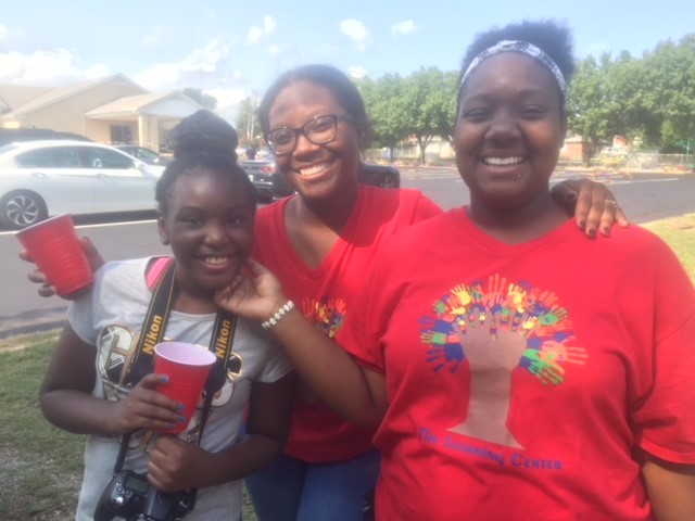 Three girls in red t - shirts smiling for the camera.