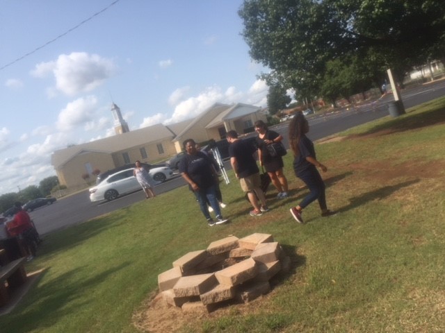 A group of people standing around a fire pit.