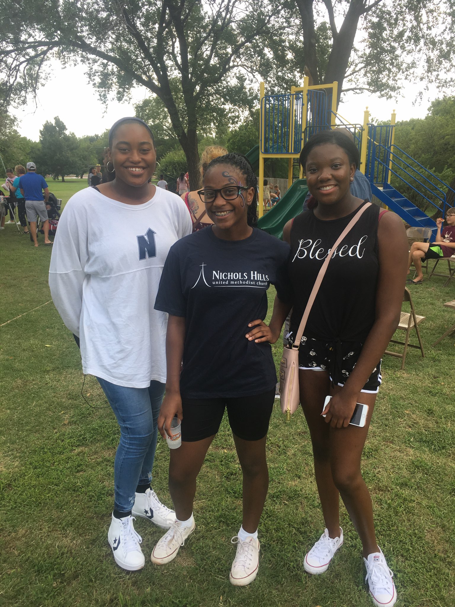 Three young women posing for a picture in a park.