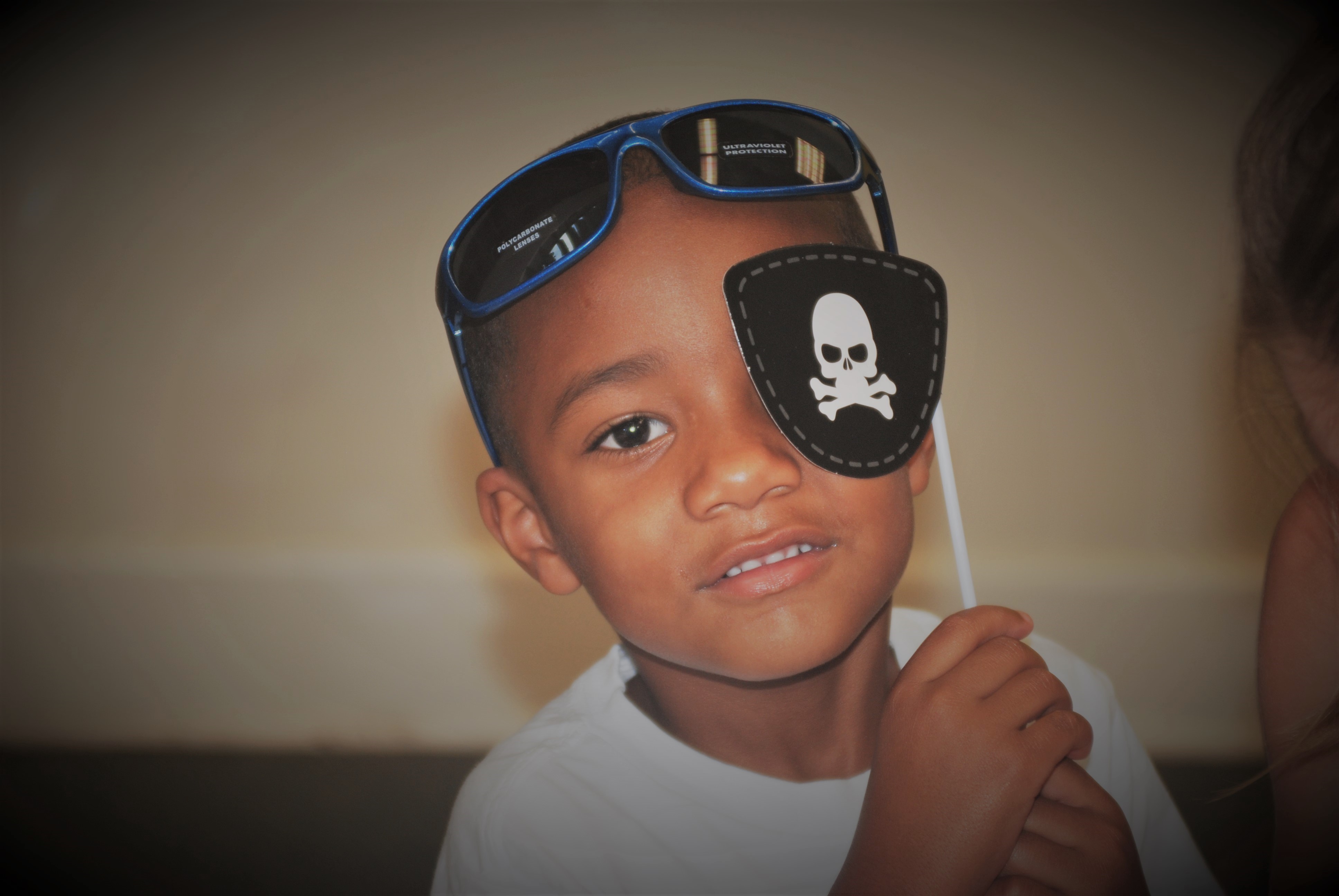 A young boy wearing sunglasses and a pirate mask.