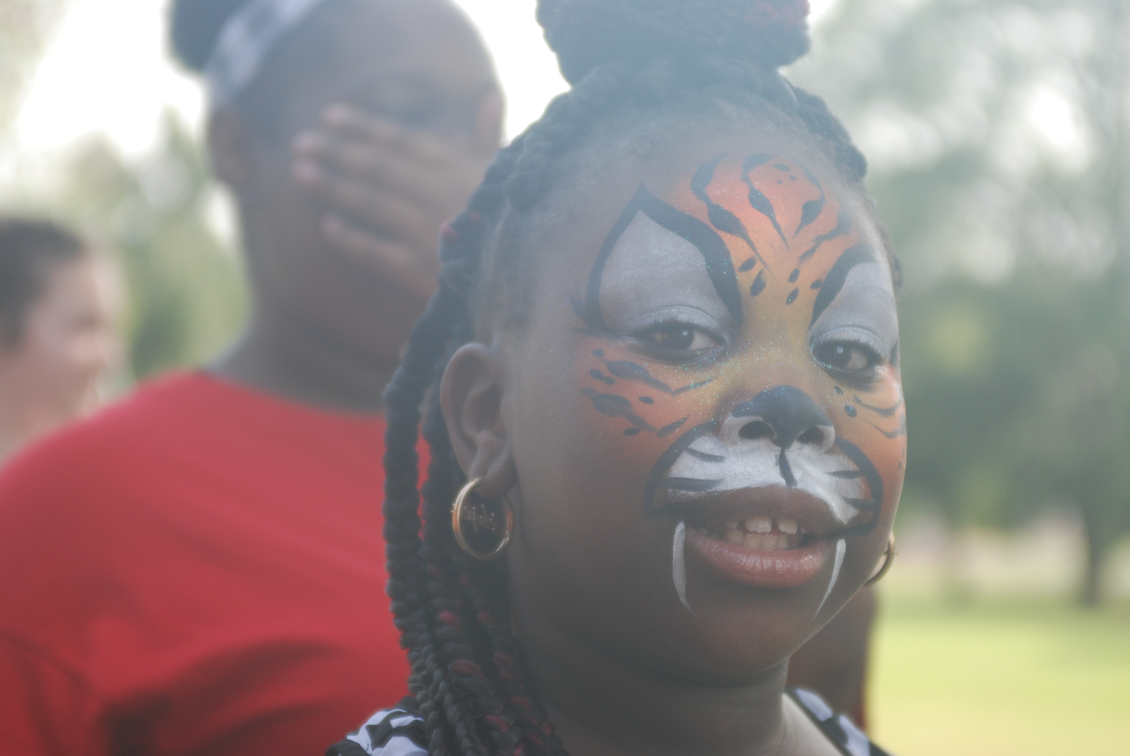 A girl with a tiger face painted on her face.