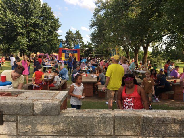 A crowd of people at a picnic in a park.