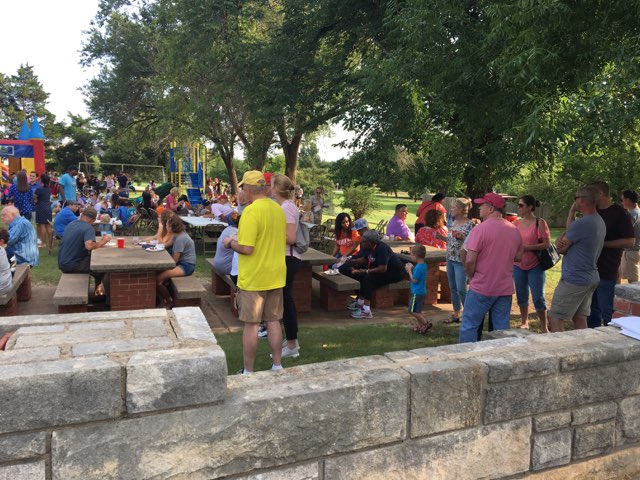 A group of people gathered at a picnic table in a park.