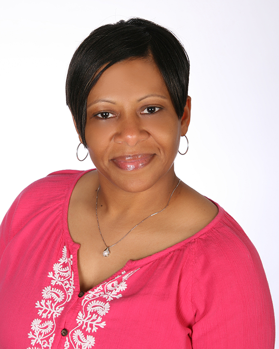 A black woman in a pink top posing for a photo.