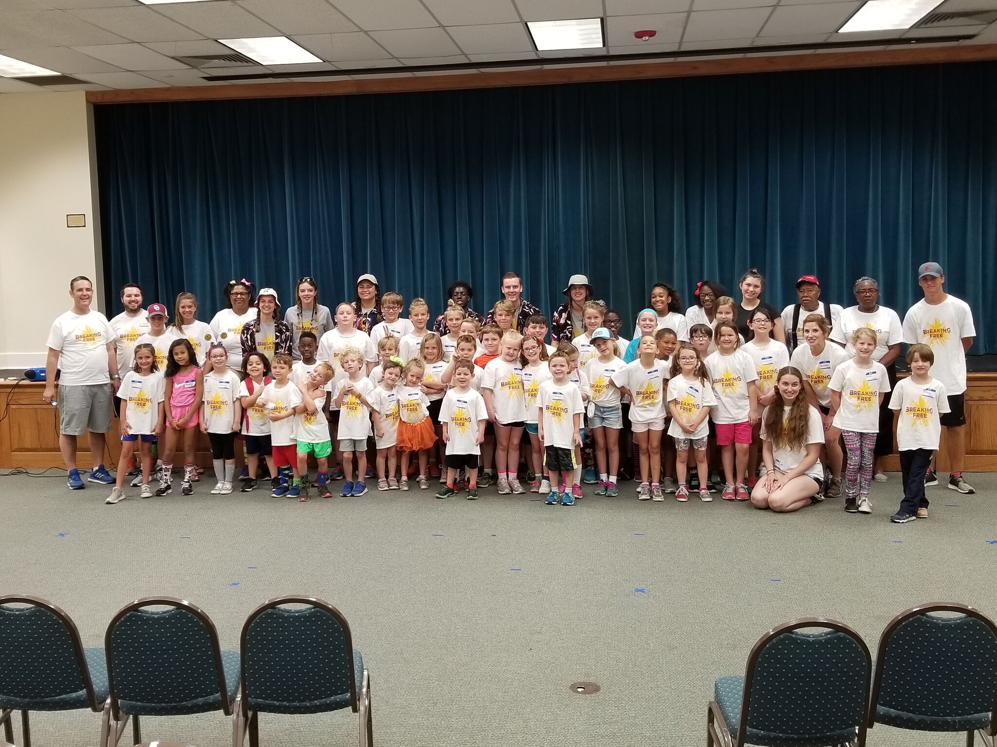 A group of children posing for a picture in front of a stage.